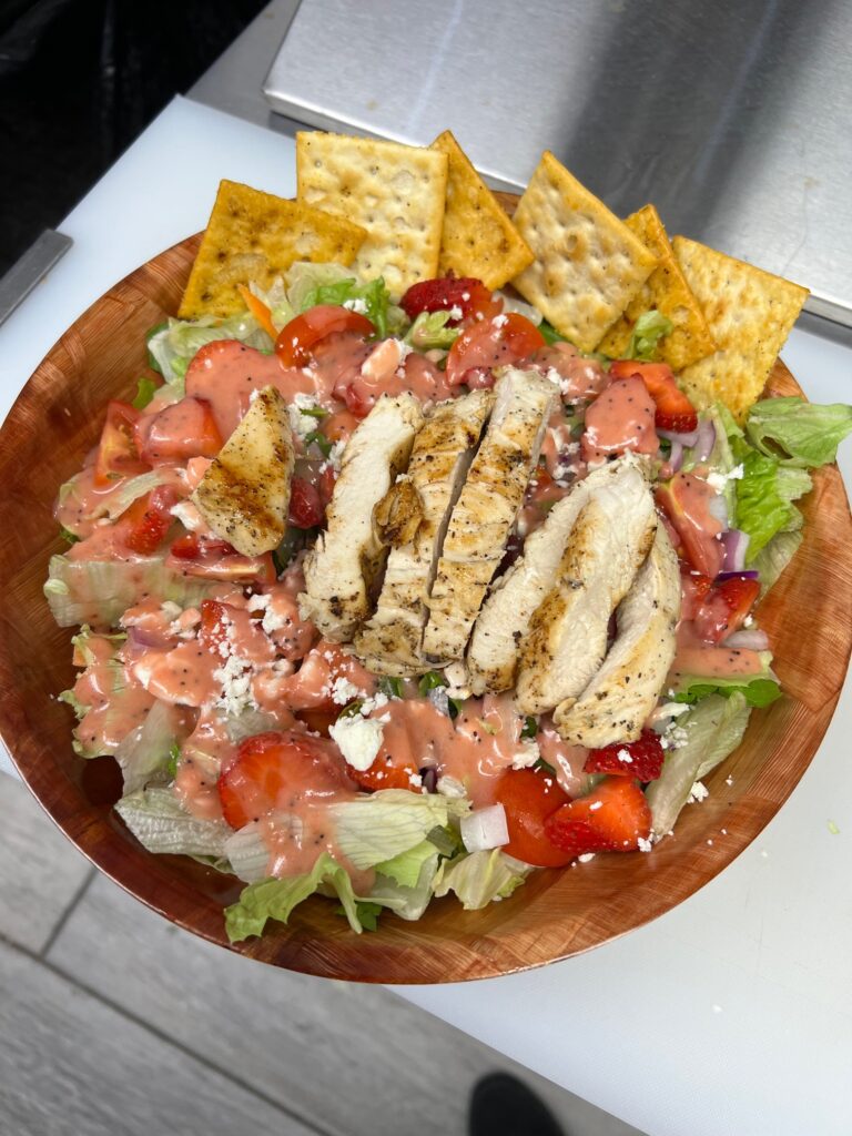Salad topped with lush strawberries and fresh-grilled chicken on a bed of iceburg lettuce with crackers on the side